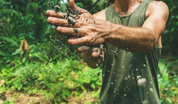 גבר בשטח מחכך את ידיו המלוכלכות אחת בשניה
